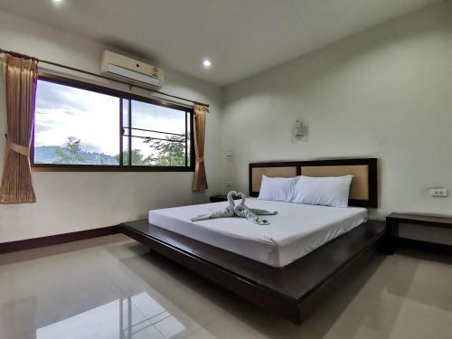 a bedroom with a large white bed with a window at Nestvilla Khok-kloi Phang-nga in Ban Nai