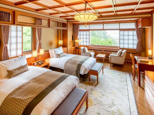 Habitación de hotel con 2 camas y sala de estar. en Fujiya Hotel, en Hakone