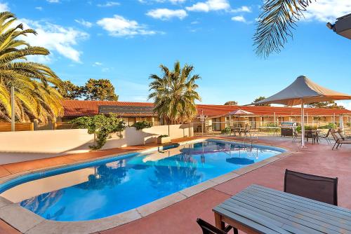 a swimming pool with a picnic table next to a house at Comfort Inn Whyalla in Whyalla