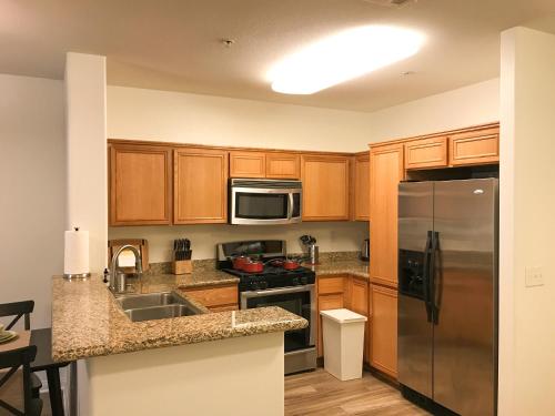 a kitchen with wooden cabinets and a stainless steel refrigerator at Perfect Apt near UCLA w Parking Gym Pool WIFI in Westwood B3 in Los Angeles