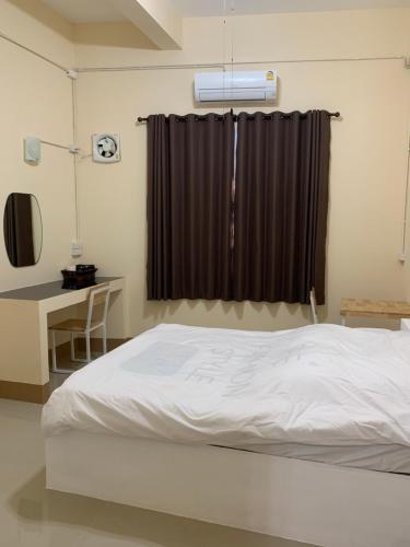 a bedroom with a bed and a desk and a window at Tk Home 1 in Lampang
