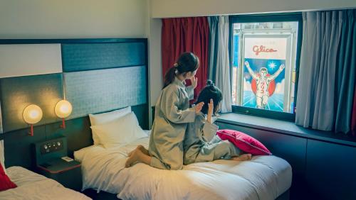a woman sitting on a bed in a hotel room at Cross Hotel Osaka in Osaka