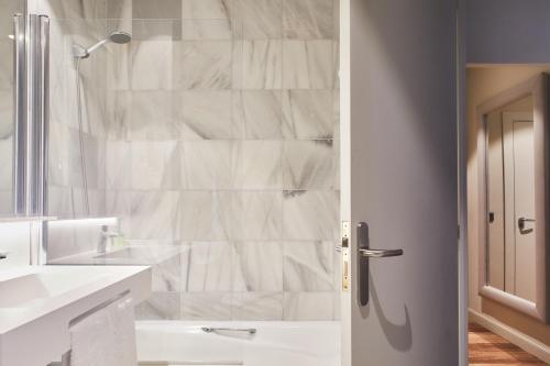 a white bathroom with a shower and a sink at Hotel Silken Palacio Uribarren in Lekeitio