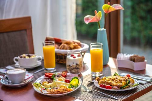 a table topped with plates of food and orange juice at Budapest Airport Hotel Stáció Superior Wellness & Konferencia in Vecsés