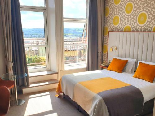 a bedroom with a bed and two windows at The Address Cork (formerly Ambassador Hotel & Health Club) in Cork