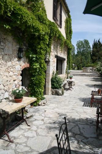 a stone patio with a table and chairs and a building at Hotel-Restaurant Le Moulin De La Camandoule in Fayence