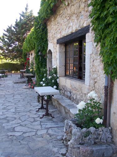 a stone building with a bench in front of it at Hotel-Restaurant Le Moulin De La Camandoule in Fayence