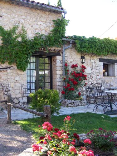 a stone building with a table and chairs and flowers at Hotel-Restaurant Le Moulin De La Camandoule in Fayence