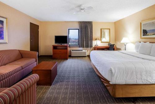 a hotel room with a large bed and a couch at La Quinta Inn by Wyndham Detroit Southgate in Southgate