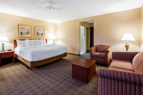 a hotel room with a bed and two chairs at La Quinta Inn by Wyndham Detroit Southgate in Southgate