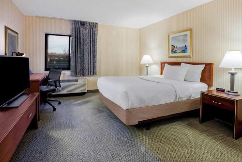 a hotel room with a bed and a desk and a television at La Quinta Inn by Wyndham Detroit Southgate in Southgate