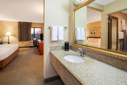 a hotel room with a bathroom with a sink and a bed at La Quinta Inn by Wyndham Detroit Southgate in Southgate