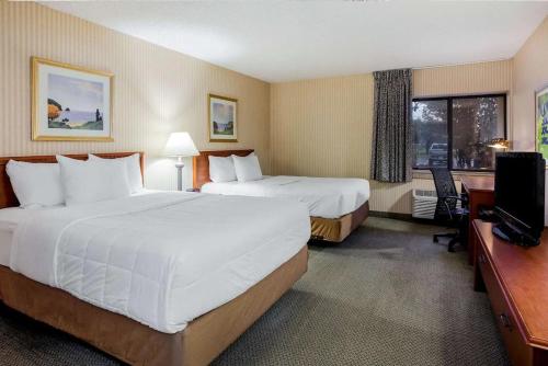 a hotel room with two beds and a television at La Quinta Inn by Wyndham Detroit Southgate in Southgate