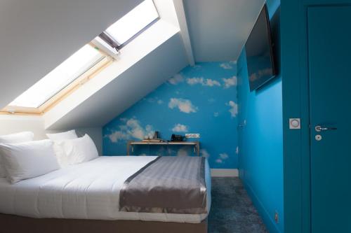 - une chambre dotée d'un lit avec un mur bleu dans l'établissement Hotel Sixteen Paris Montrouge, à Montrouge