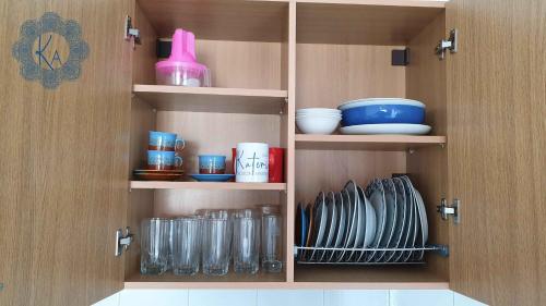 une armoire remplie de assiettes, de bols et de verres dans l'établissement Katerina Rodon Apartments, à Nea Roda