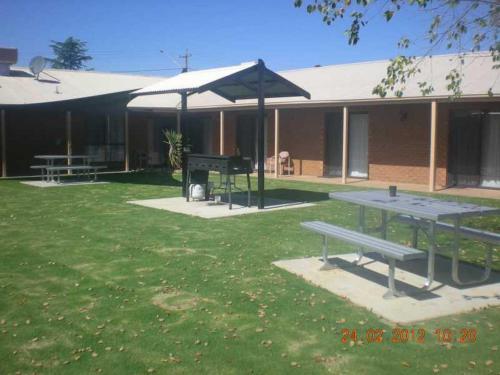 a picnic table and a grill in front of a building at Ashleigh Court Motor Inn in Mulwala