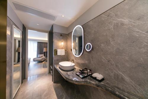 a bathroom with a sink and a mirror on a wall at Mercure Turpan Downtown in Turfan