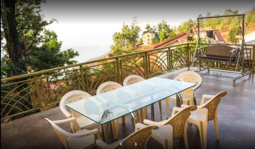 een tafel en stoelen op een balkon met een piano bij Sweden Villa 4BHK in Panchgani