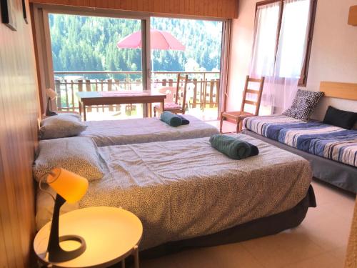 a bedroom with two beds and a balcony at Village vacances Le Savoy in Le Grand-Bornand