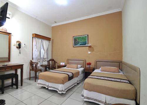 a hotel room with two beds and a desk at Hotel Mataram Malioboro in Yogyakarta