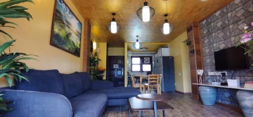 a living room with a blue couch and a table at My Home Apartment - Villa Dahlia Apartment in Cameron Highlands