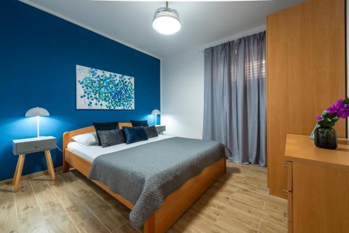 ein Schlafzimmer mit einem Bett und einer blauen Wand in der Unterkunft Ellanna in Mlini