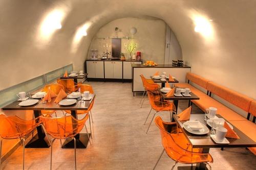 un ristorante con tavoli e sedie arancioni e una cucina di Hotel Svambersky dum a Cesky Krumlov