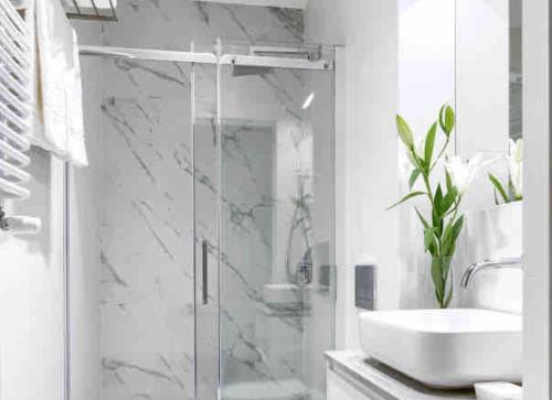 La salle de bains blanche est pourvue d'un lavabo et d'une douche. dans l'établissement Apartament przy Targach Poznań, à Poznań