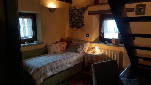 a small bedroom with a bed and two windows at HOME SWEET HOME in Antey-Saint-André