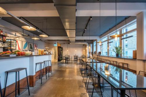 un restaurante con un bar largo con taburetes en CPH Studio Hotel, en Copenhague