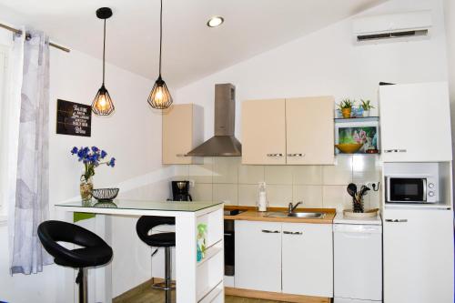 eine Küche mit weißen Schränken und schwarzen Barhockern in der Unterkunft Tamaris in Sevid