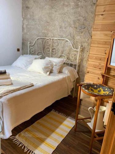 a bedroom with a white bed with a table and a tableasteryasteryasteryastery at Casa Rural El Pajarcillo in Moriana