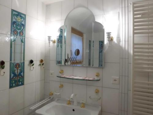 a white bathroom with a sink and a mirror at Matti-Tinoll in Grimentz