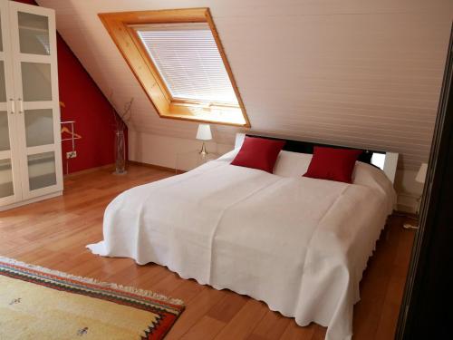a bedroom with a white bed with two red pillows at Ferienwohnung Günther in Lauf an der Pegnitz