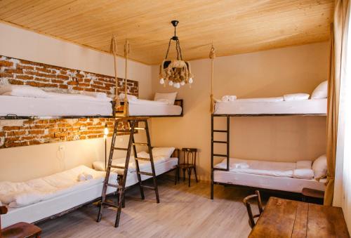 a room with three bunk beds and a wooden ceiling at Home Kazbegi in Stepantsminda