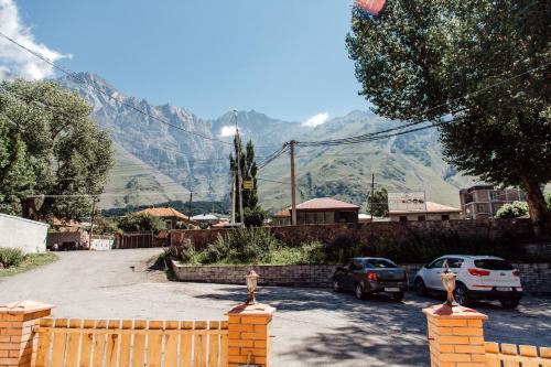 a parking lot with cars parked in front of a mountain at Home Kazbegi in Stepantsminda