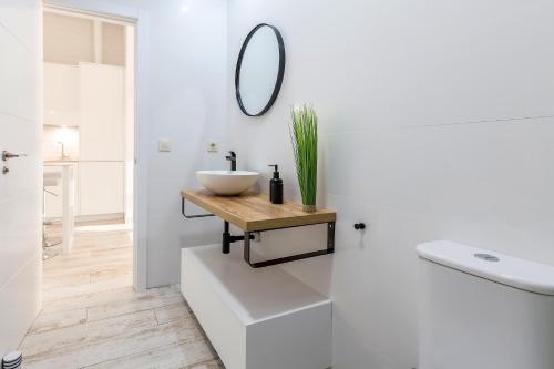 a white bathroom with a sink and a mirror at Bajo con Jardin y Piscina cerca de la Playa Dos Dormitorios in Tarifa