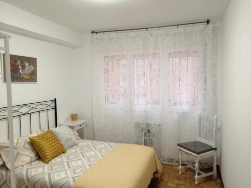 a bedroom with a bed and a chair and a window at Apartamento Quety Gijón in Gijón