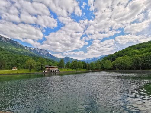 a lake in the mountains with a house on the shore at Vila "Volujak" in Tjentište