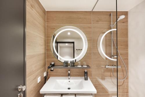 a bathroom with a sink, toilet and mirror at H2 Hotel Leipzig in Leipzig