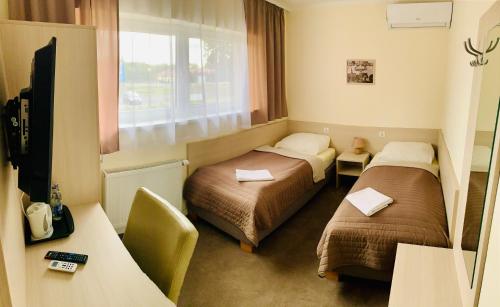 a hotel room with two beds and a television at Gościniec Skwierzyna in Skwierzyna