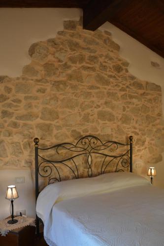 a bed in a room with a stone wall at B&B Le Fate in Sonnino