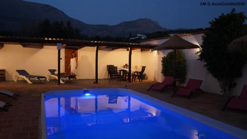 a swimming pool in front of a house at night at Casa La Negra in Periana