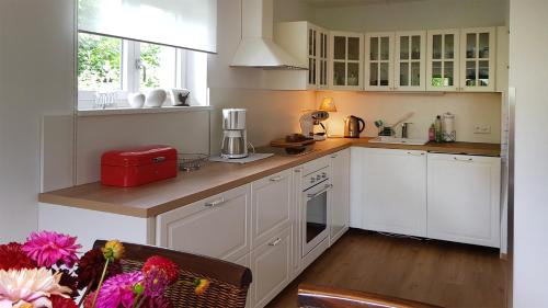 uma cozinha com armários brancos e um aparelho vermelho em Villa Piccola em Villach