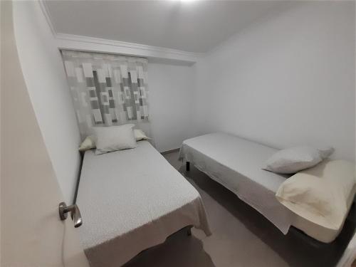 a white room with two beds and a window at Apartamento Portalet 7 in Benaguacil