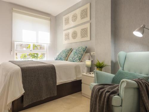sypialnia z łóżkiem i 2 niebieskimi krzesłami w obiekcie Misterhost San Bernardo Jardines de Murillo w Sewilli