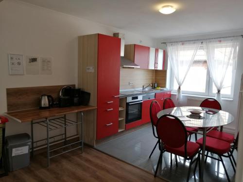 cocina con armarios rojos, mesa y sillas en Apartment AMS en Oststeinbek