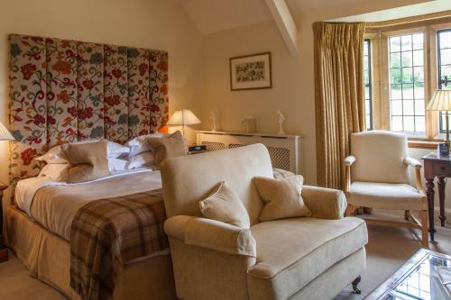 a bedroom with a bed and a chair at Buckland Manor - A Relais & Chateaux Hotel in Broadway