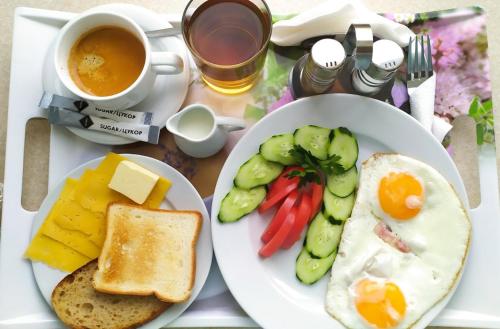 a table with two plates of breakfast foods and a cup of coffee at ApartHotel on Klinichna st. (1st entrance) in Kyiv