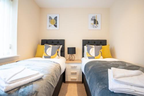two beds in a small room with yellow and blue at Apartment 9 in Worksop